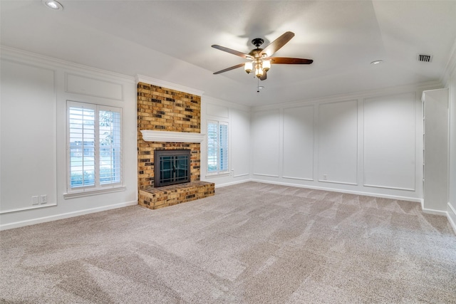 unfurnished living room featuring a brick fireplace, ceiling fan, visible vents, and light carpet