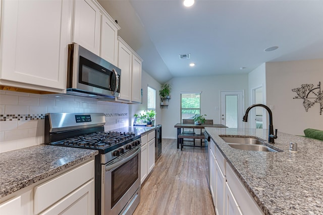 kitchen with light stone counters, a sink, light wood-style flooring, and appliances with stainless steel finishes