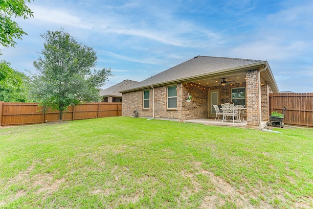 back of property featuring a fenced backyard, a ceiling fan, a yard, and brick siding
