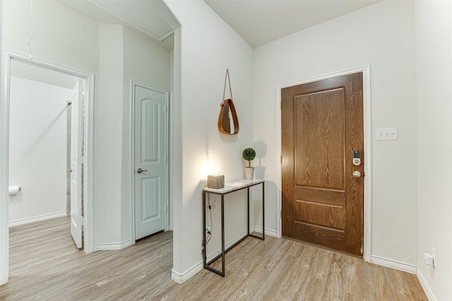 entrance foyer with arched walkways, baseboards, and light wood-type flooring