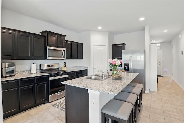 3613 Ridgeway Ln, Denton, TX 76226 - kitchen with stainless steel appliances, a sink, light tile patterned floors, recessed lighting, and a kitchen island with sink