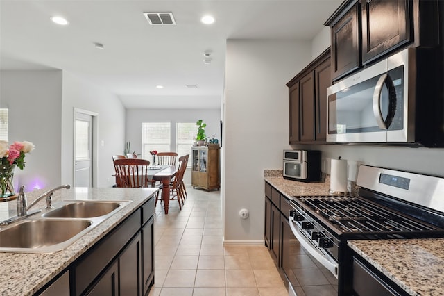 3613 Ridgeway Ln, Denton, TX 76226 - kitchen featuring appliances with stainless steel finishes, a sink, light tile patterned floors, dark brown cabinets, and recessed lighting