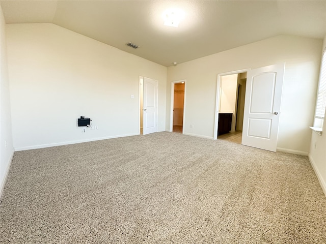 unfurnished bedroom featuring visible vents, baseboards, lofted ceiling, and a spacious closet