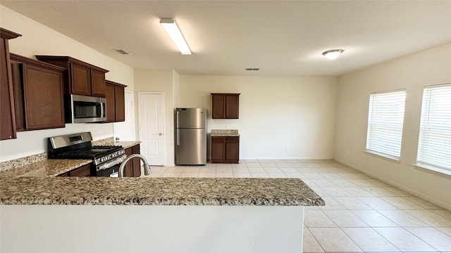 kitchen featuring stainless steel appliances, dark brown cabinetry, visible vents, and a sink
