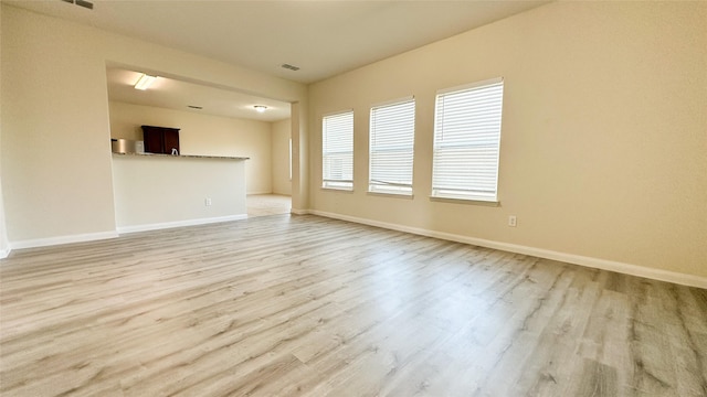 unfurnished living room featuring baseboards, visible vents, and light wood-type flooring