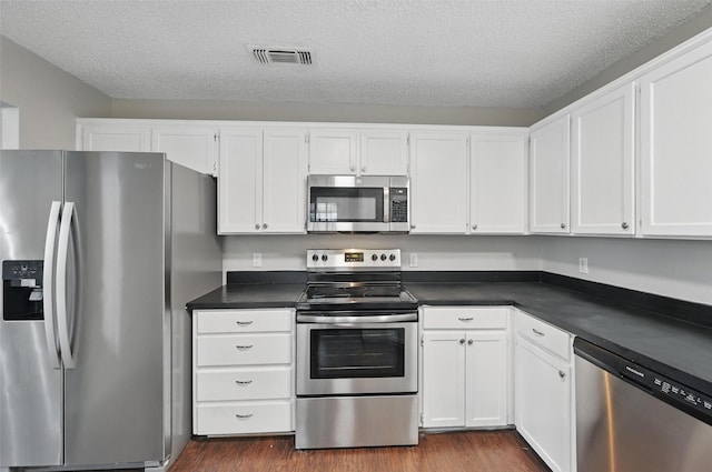 6317 N Park Dr, Watauga, TX 76148 - kitchen with stainless steel appliances, dark wood-style flooring, and white cabinetry