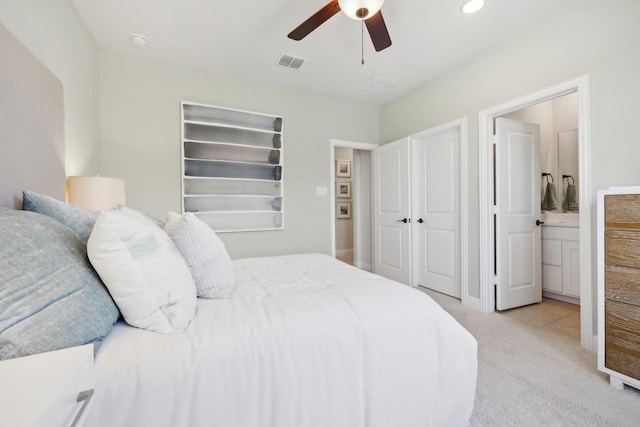 bedroom with a ceiling fan, light colored carpet, connected bathroom, and visible vents