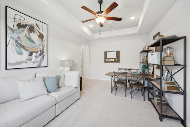 living room with visible vents, baseboards, light colored carpet, a tray ceiling, and a ceiling fan