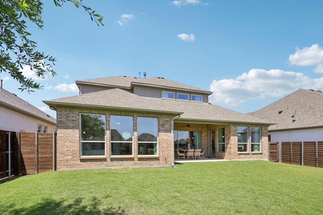 back of house featuring roof with shingles, a lawn, brick siding, a fenced backyard, and a patio