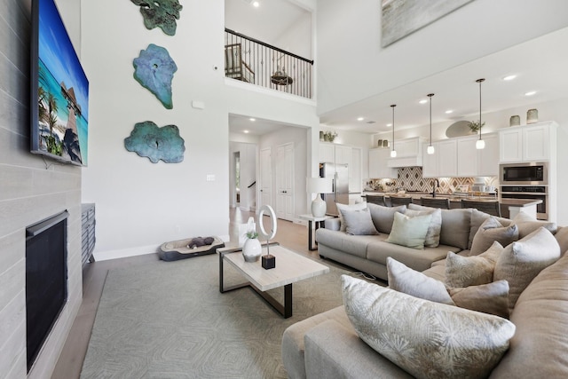 living room featuring a glass covered fireplace, baseboards, recessed lighting, and wood finished floors