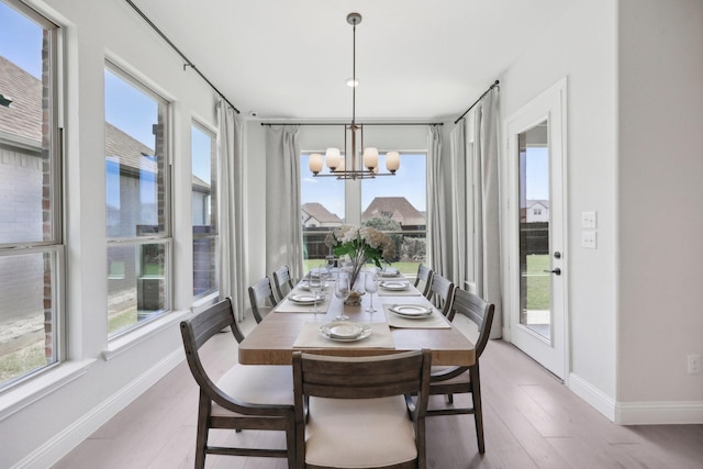 dining room with a wealth of natural light, light wood-style flooring, and a notable chandelier