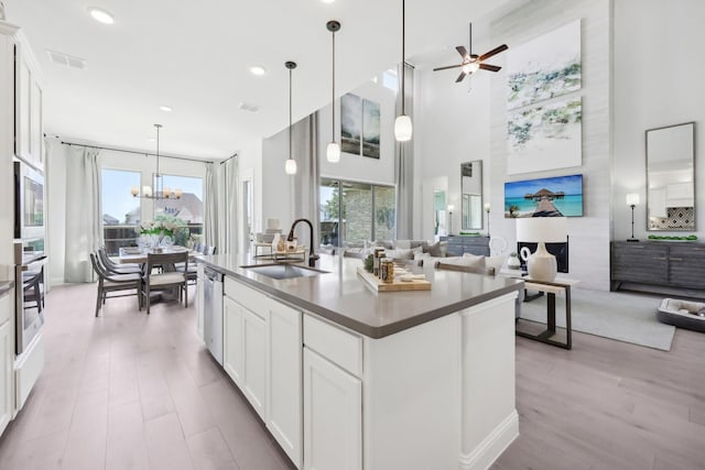 kitchen with visible vents, appliances with stainless steel finishes, a sink, open floor plan, and light wood-style floors