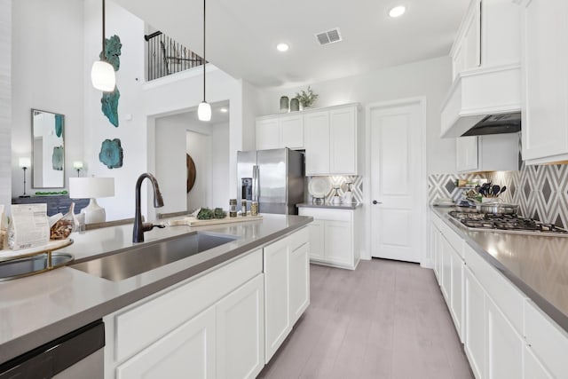 kitchen featuring a sink, appliances with stainless steel finishes, white cabinets, and backsplash