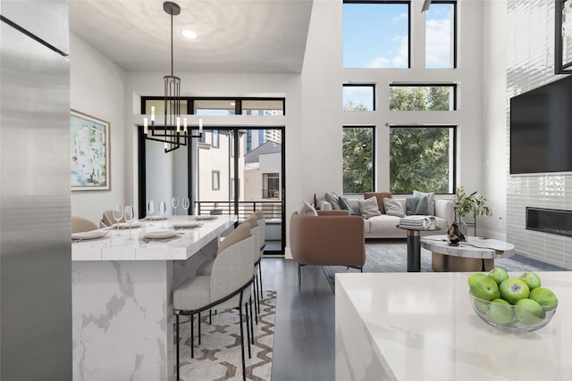 dining room featuring a healthy amount of sunlight, an inviting chandelier, a fireplace, and a high ceiling