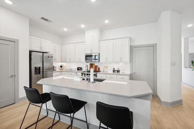 8613 Keeneland Dr, Fort Worth, TX 76120 - kitchen with a kitchen bar, appliances with stainless steel finishes, light countertops, white cabinets, and light wood-style floors