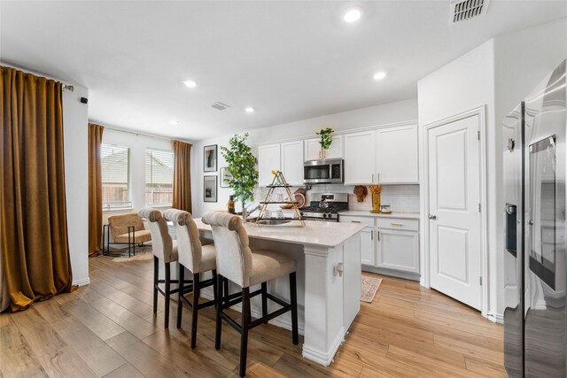 859 Sitwell Dr, Fate, TX 75087 - kitchen with a breakfast bar area, visible vents, light countertops, stainless steel appliances, and white cabinetry