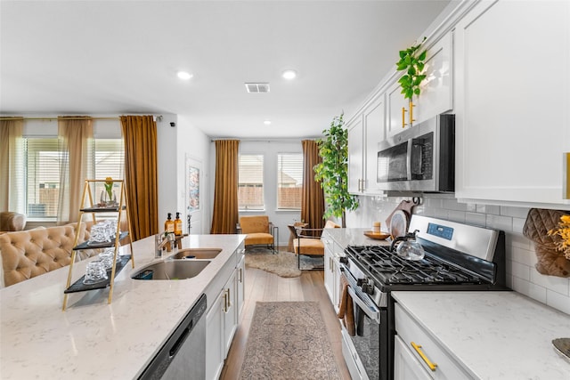 859 Sitwell Dr, Fate, TX 75087 - kitchen with visible vents, white cabinetry, a sink, appliances with stainless steel finishes, and backsplash