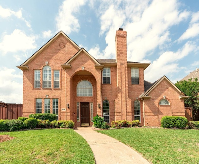 view of front of property with brick siding, a chimney, and a front yard