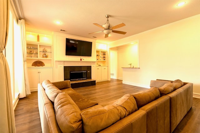 living room with ceiling fan, baseboards, wood finished floors, a tile fireplace, and ornamental molding