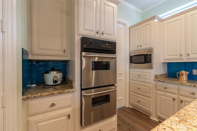 kitchen featuring ornamental molding, decorative backsplash, wood finished floors, light stone countertops, and appliances with stainless steel finishes
