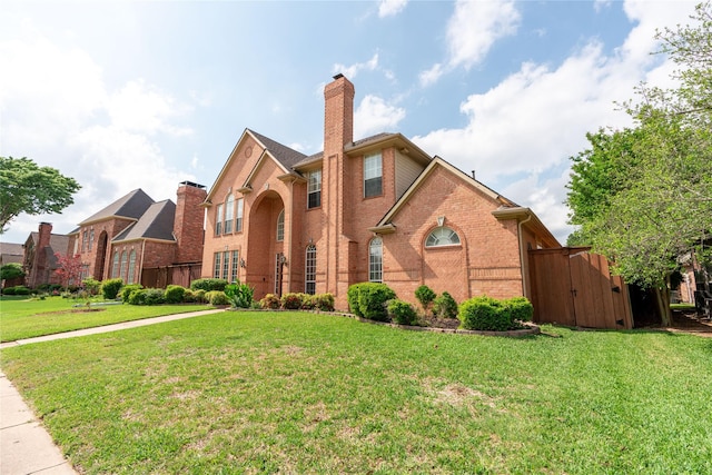 traditional-style home with brick siding, a storage unit, a chimney, and a front lawn
