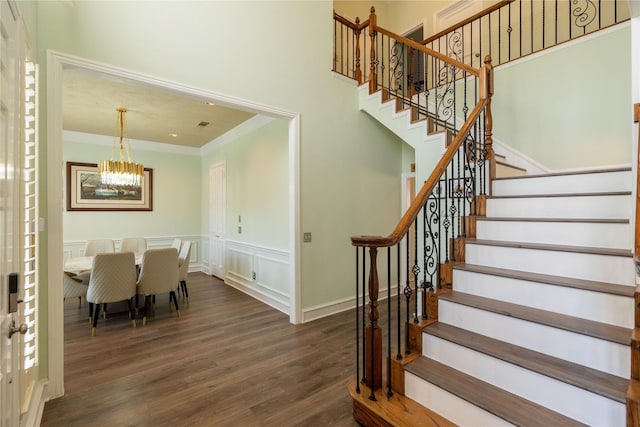 stairway featuring baseboards, ornamental molding, wood finished floors, and a chandelier