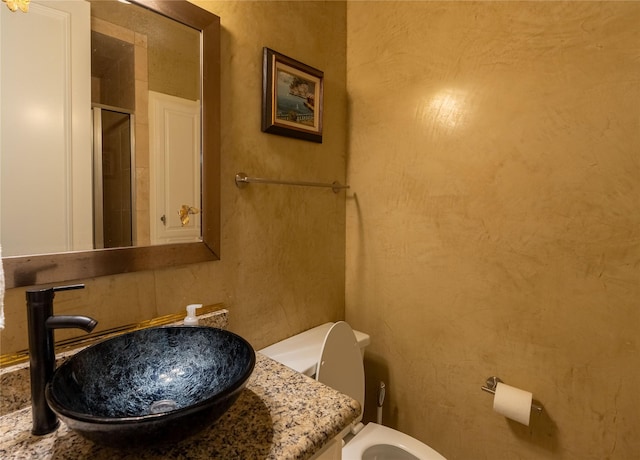 bathroom with toilet, a shower with door, and vanity