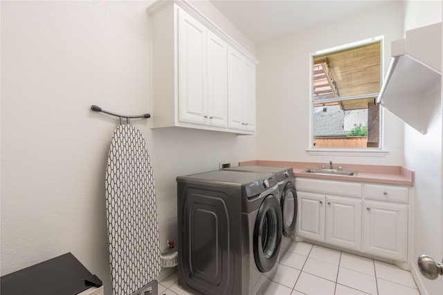 laundry area featuring a sink, light tile patterned floors, washing machine and dryer, and cabinet space