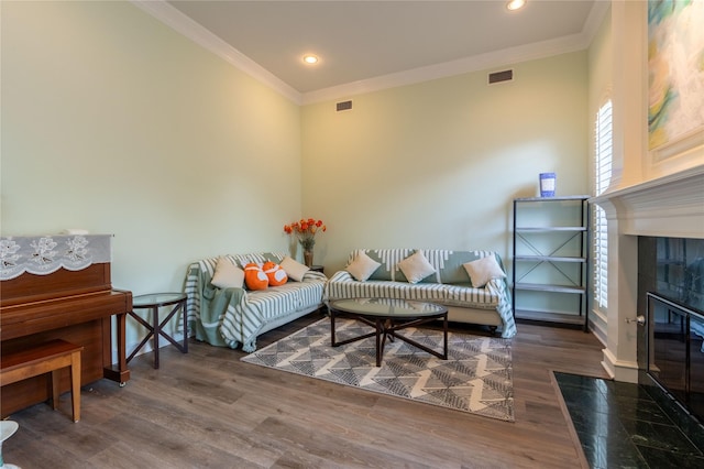 living room featuring visible vents, ornamental molding, baseboards, and wood finished floors