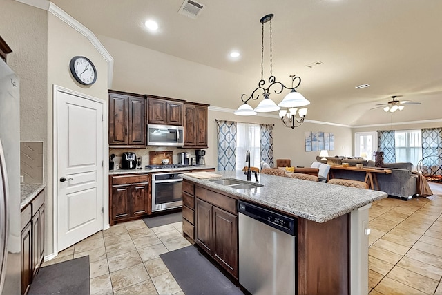 733 Ravenwood Dr, Saginaw, TX 76179 - kitchen featuring appliances with stainless steel finishes, a sink, open floor plan, light tile patterned flooring, and healthy amount of natural light