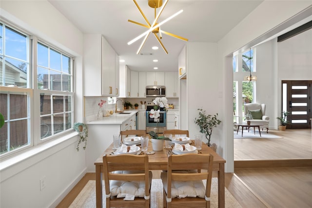 dining space featuring recessed lighting, a notable chandelier, visible vents, and light wood finished floors