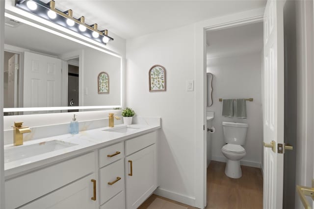 bathroom with toilet, visible vents, a sink, and wood finished floors