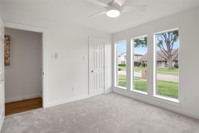 carpeted empty room with baseboards and a ceiling fan