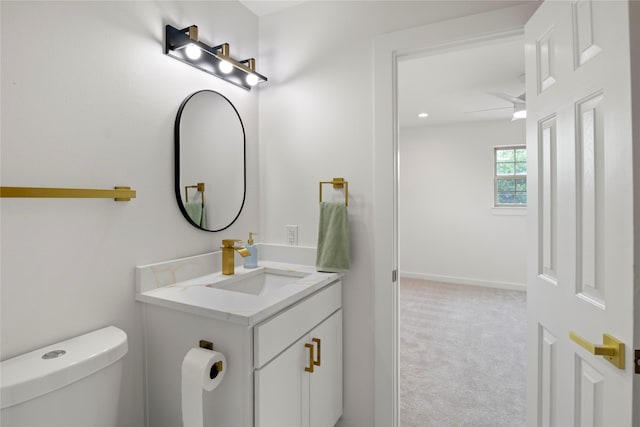 half bathroom with vanity, baseboards, and toilet