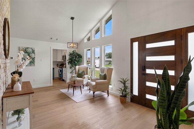 entrance foyer featuring visible vents, light wood finished floors, baseboards, and high vaulted ceiling