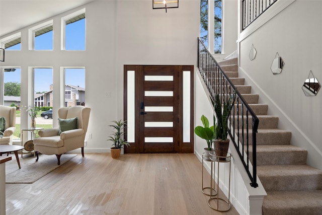 foyer with stairs, baseboards, plenty of natural light, and wood finished floors