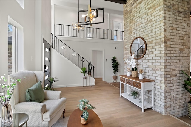 foyer entrance featuring baseboards, a notable chandelier, wood finished floors, and a high ceiling