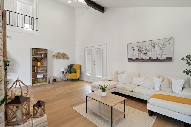 living room featuring beam ceiling, ceiling fan, high vaulted ceiling, french doors, and light wood-style flooring