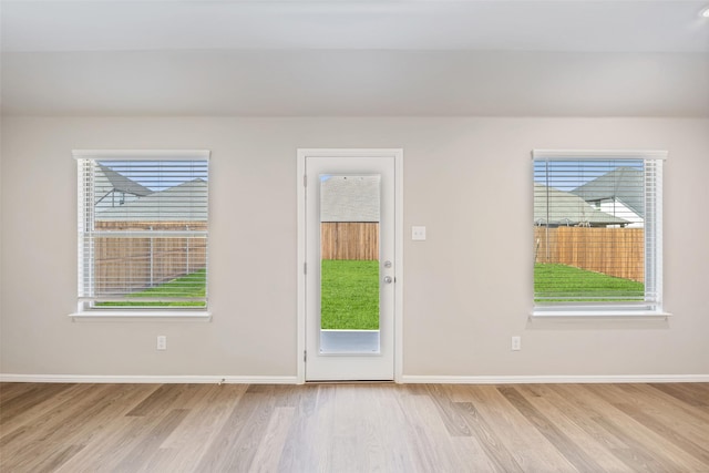 doorway featuring a healthy amount of sunlight, baseboards, and wood finished floors