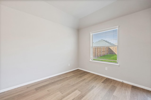 spare room featuring baseboards and light wood finished floors