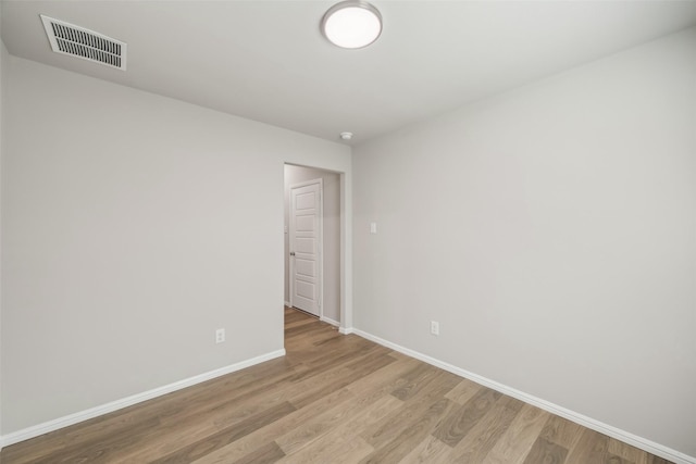 empty room featuring baseboards, wood finished floors, and visible vents
