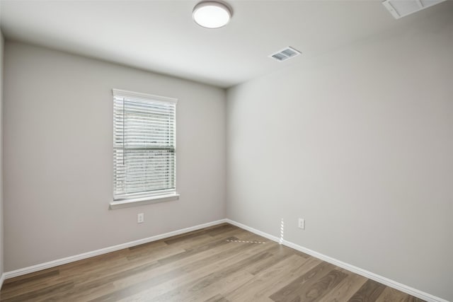 empty room featuring visible vents, a wealth of natural light, and wood finished floors