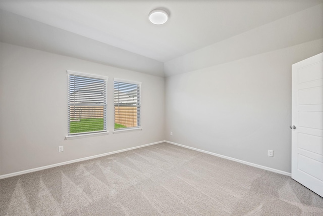 unfurnished room featuring baseboards, carpet, and vaulted ceiling