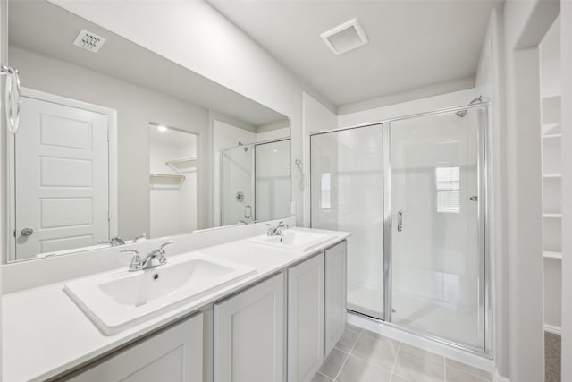 bathroom with a sink, a shower stall, double vanity, and visible vents
