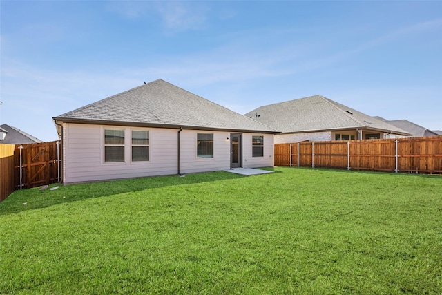 rear view of property featuring a lawn, a fenced backyard, and roof with shingles