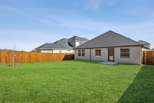back of house featuring a lawn, a shingled roof, and a fenced backyard