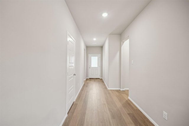 hallway with baseboards, recessed lighting, and light wood-style floors
