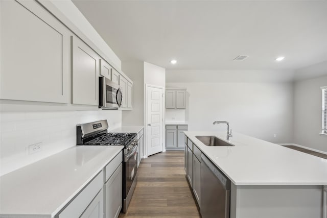 kitchen with decorative backsplash, gray cabinets, a sink, stainless steel appliances, and recessed lighting