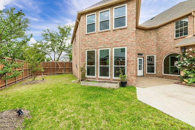 back of house featuring roof with shingles, a lawn, a patio area, brick siding, and a fenced backyard