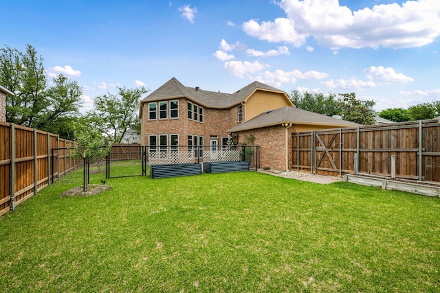back of property with brick siding, a fenced backyard, a yard, and a gate